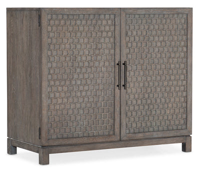A wooden Hooker Furnishings 2-Door Chest with a medium wood finish features two doors with a textured, grid-like panel design and black metal handles, set against a white background.